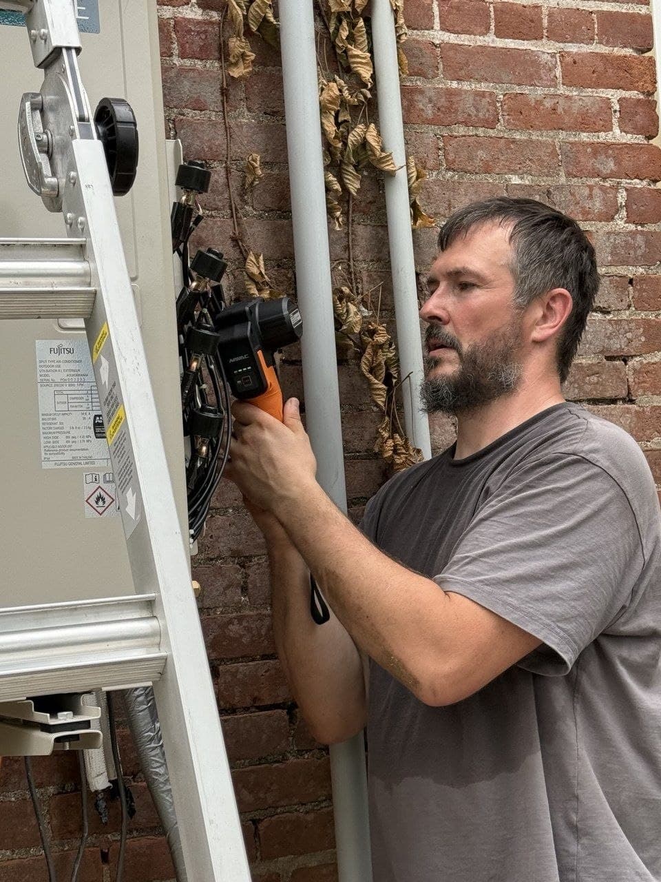 Technician installing new Fujitsu outdoor ductless split system unit